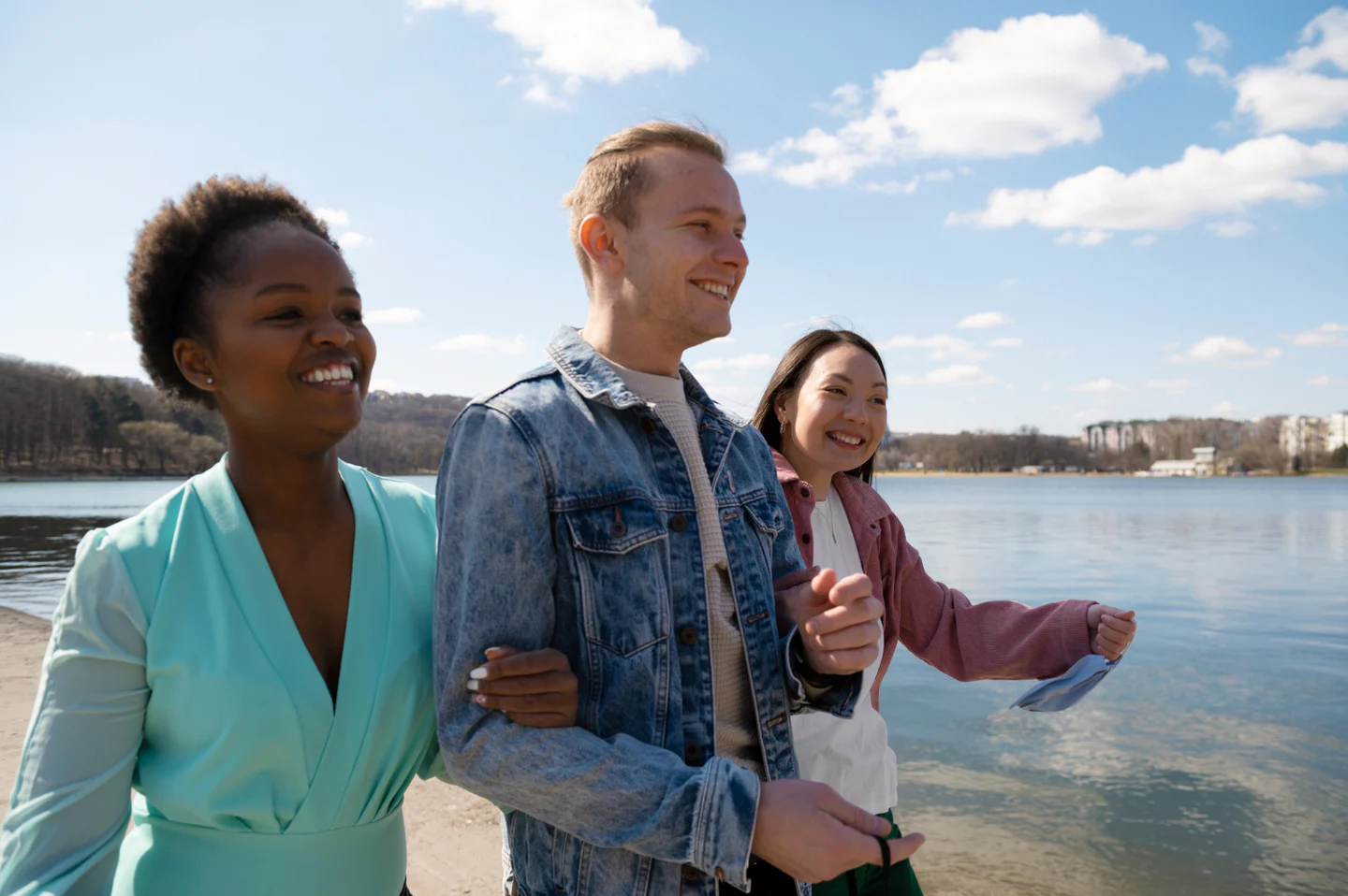Three friends walking beside a lake, representing people with different lives and dating stories